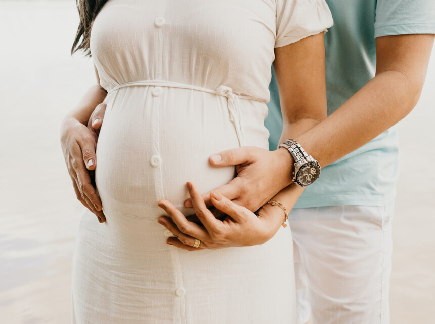 Ein Paar hat liebevoll die Hände auf den Babybauch der Frau gelegt