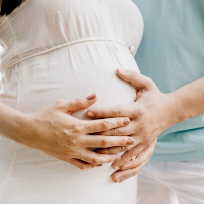 Eine Frau streichelt liebevoll ihren Babybauch