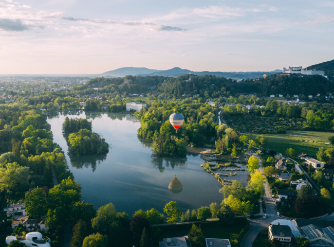 Ein Heißluftballon schwebt über einen See