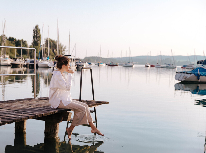 Frau sitzt am Steg mit Blick auf den Mattsee