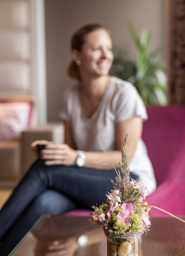 Eine Frau genießt eine Tasse Kaffee in der Lounge des Hotels Seewirt Mattsee