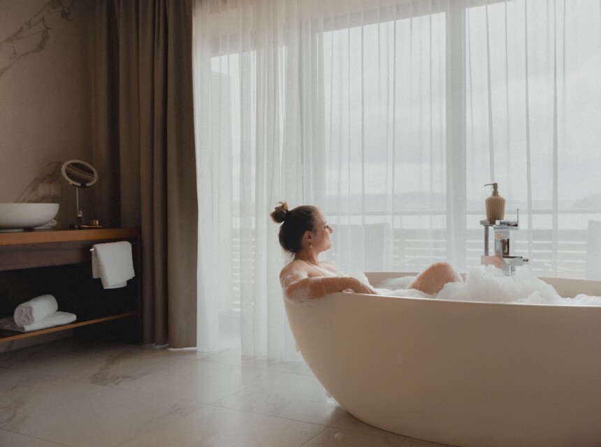 Frau liegt in der freistehenden Badewanne mit Blick auf den Mattsee 