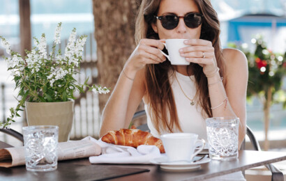 Frau sitzt auf der Terrasse mit Kaffee